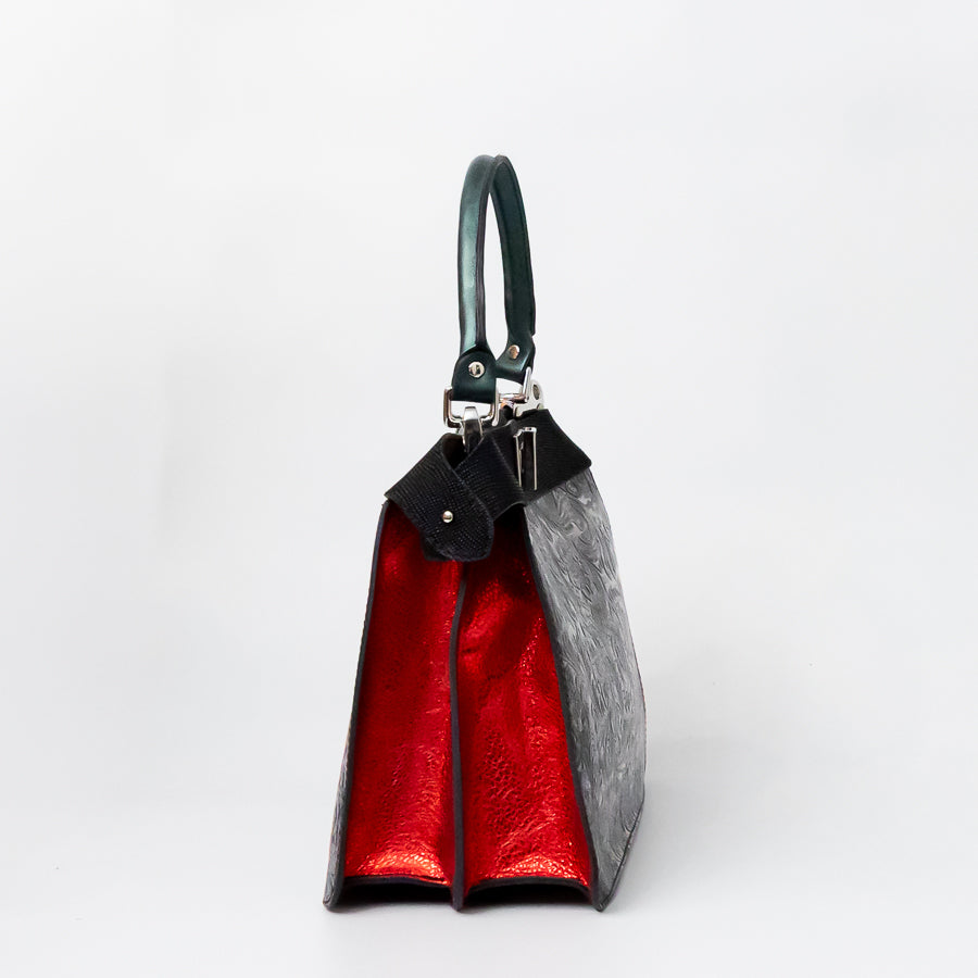 Side image of Charlotte handbag in Noir Palazzo featuring structured accordion side panels with textured red Italian leather