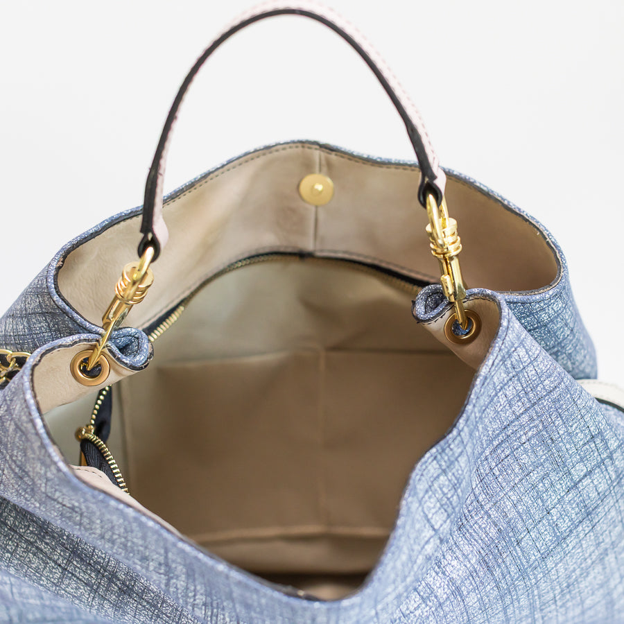 Interior image of Lily handbag in Blue Linen featuring gold hardware and two small inner pockets