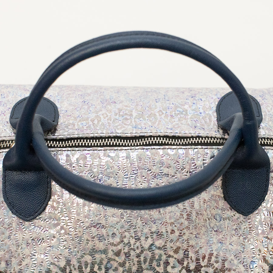 Close up image of Vera handbag in Moonlit Riviera featuring gold zipper hardware and blue structured top handles