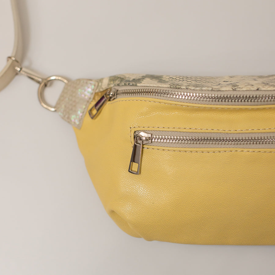 Close up image of Ava crossbody bag in Aureate featuring silver zipper hardware and textured yellow Italian leather