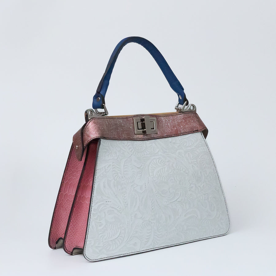Angled image of Charlotte handbag in Bianca Rosa featuring structured accordion side panels wiht pink textured Italian leather