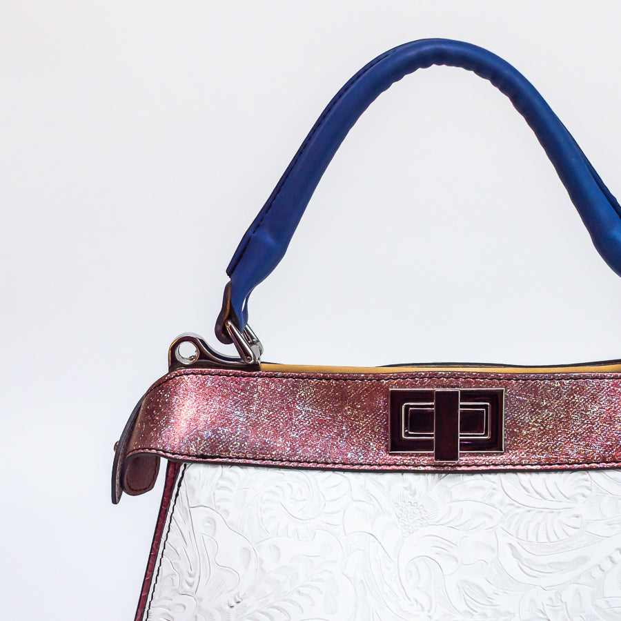 Close-up image of Charlotte handbag in Bianca Rosa featuring textured pink accent strip and blue structured top handle