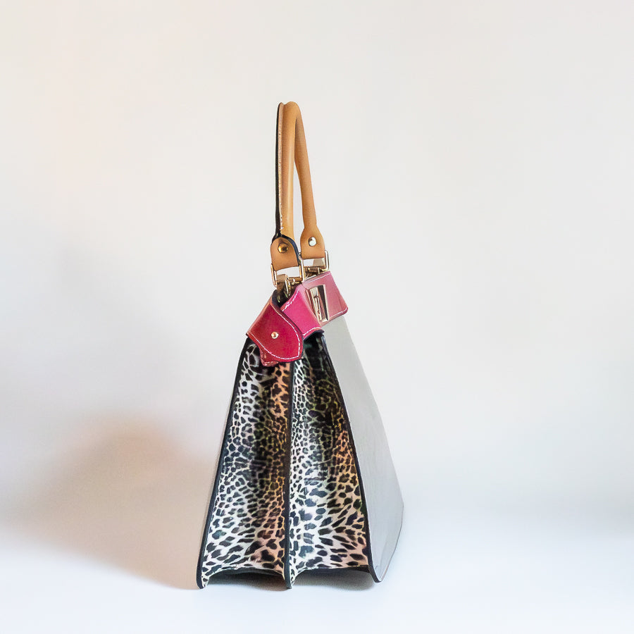 Side image of Charlotte handbag in Villa Rosa featuring structured accordion side panels with cheetah printed Italian leather 