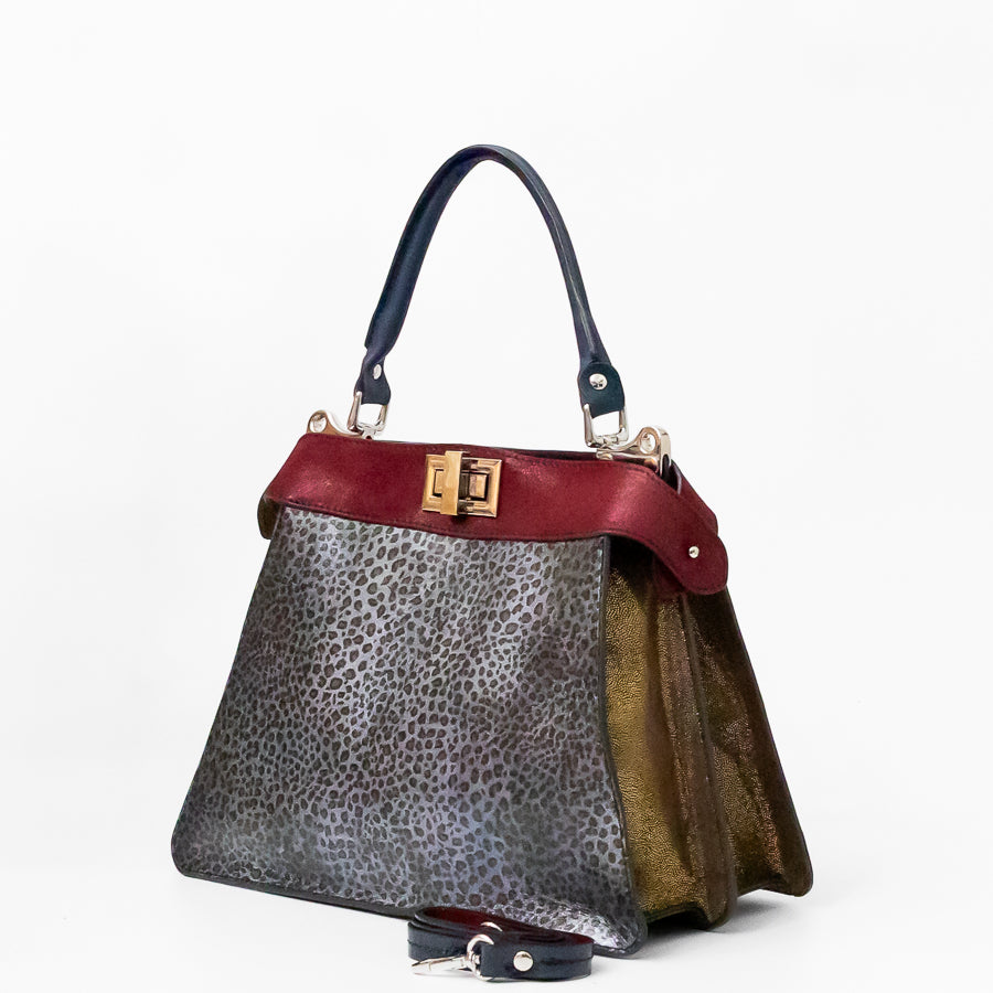Angled image of Charlotte handbag in Argenta featuring structured accordion side panels with gold Italian leather 