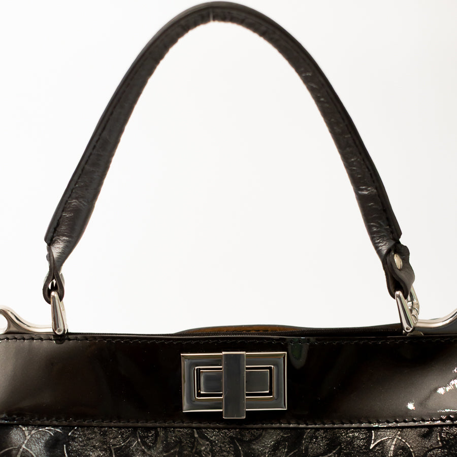 Close-up image of Charlotte handbag in Midnight Garden featuring structured top handle and silver hardware