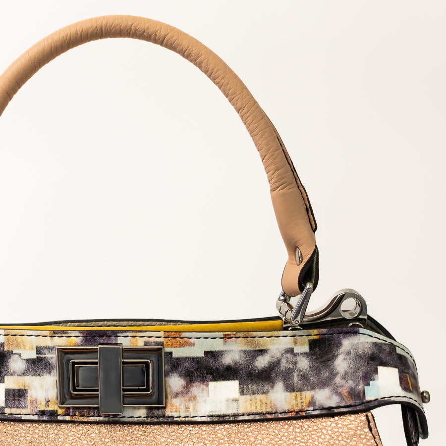 Close-up image of Charlotte handbag in Champagne Piazza featuring multicolored geometric accent strip and structured handles 