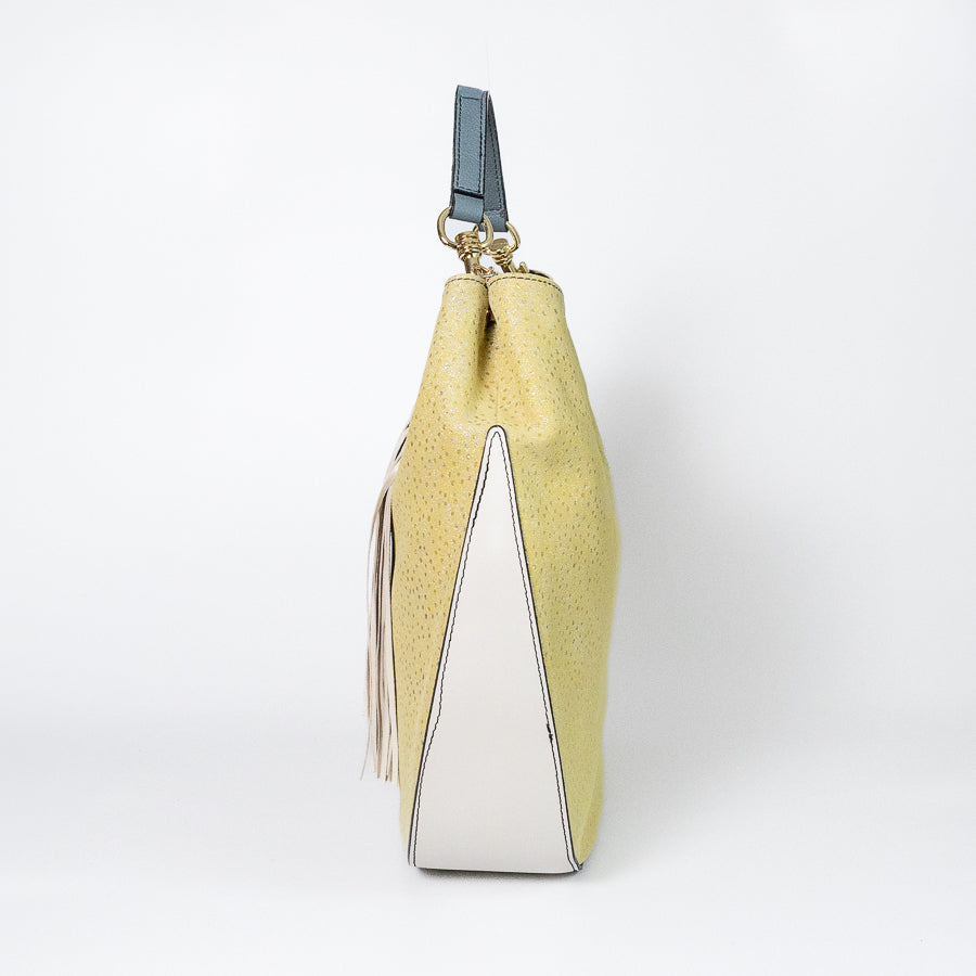 Side view of Lily handbag in Limoncello featuring blue handle and white leather on the bottom