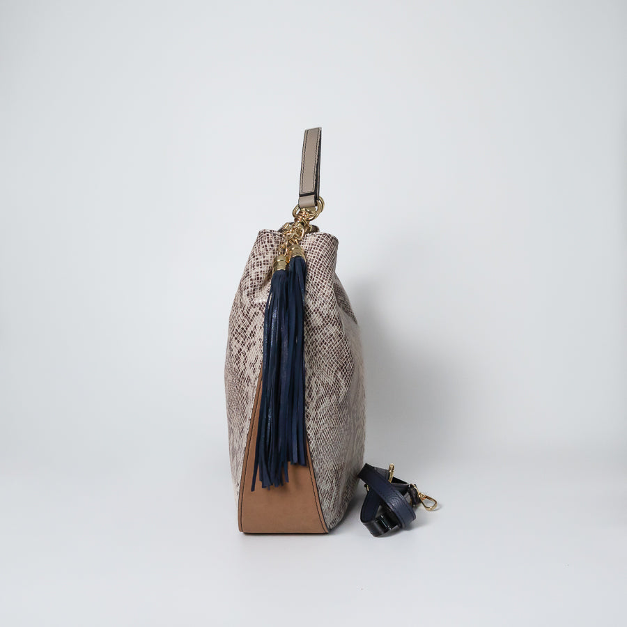 Side view of Lily handbag in Saint Tropez featuring blue tassel and brown leather bottom