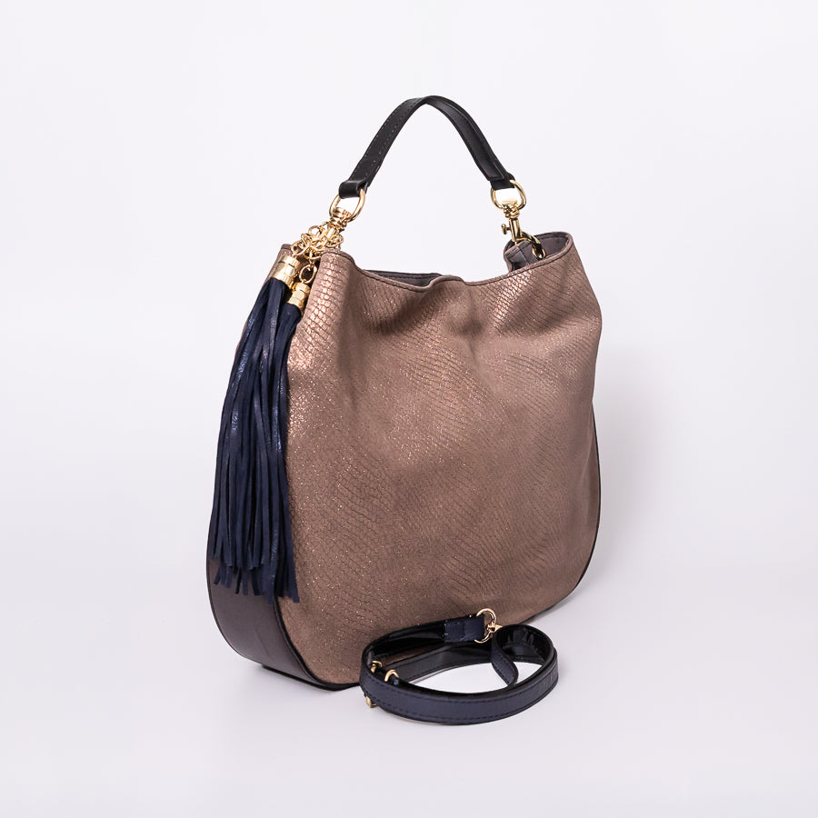 Angled view of Lily handbag in Golden Hour featuring navy tassel and black leather bottom and strap