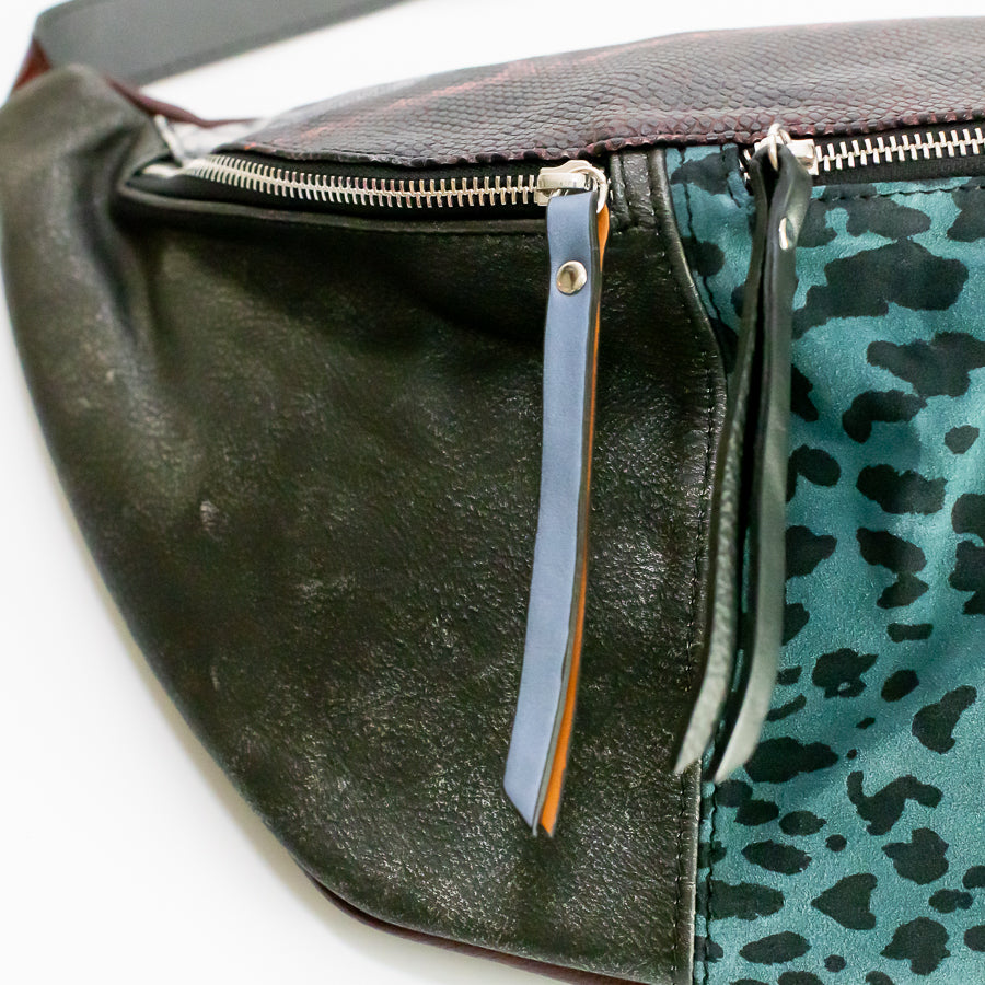 Close-up image of Madeline crossbody bag in Laguna Felina featuring green Italian leather and blue and yellow and green leather zippers