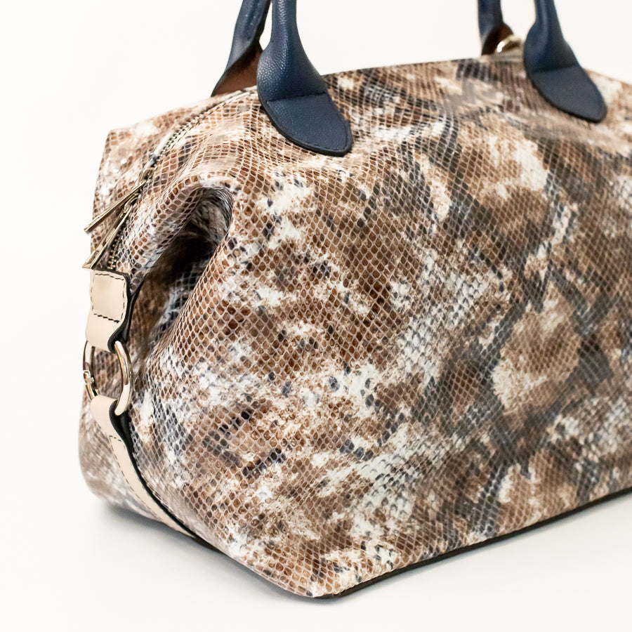 Angled image of Vera handbag in Desert Sands featuring o-ring secured side straps and snakeskin Italian leather
