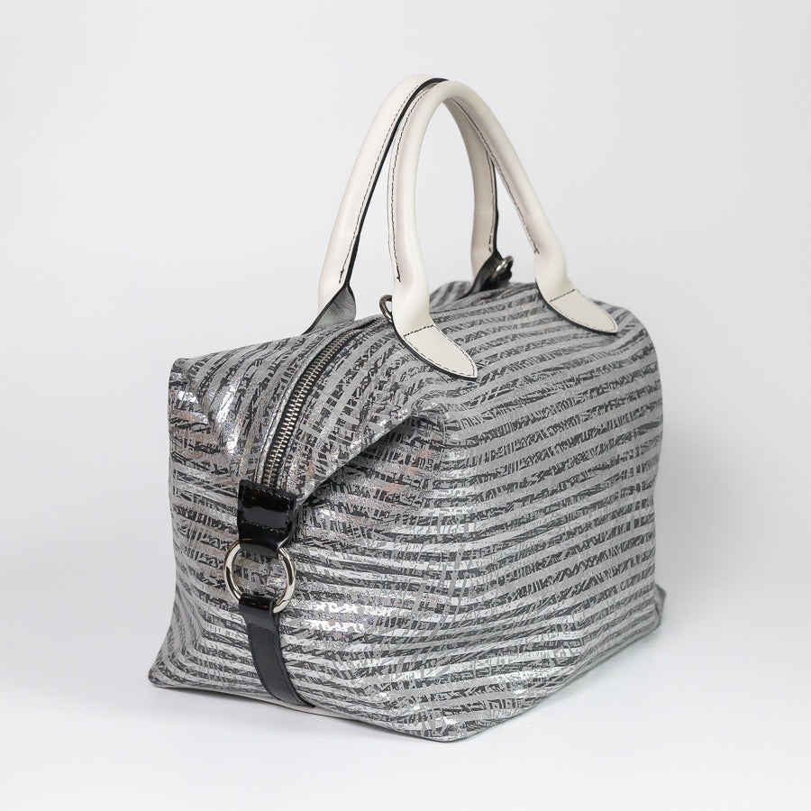 Angled image of Vera handbag in Silver Coast featuring side straps with silver o-ring clasp and top handles