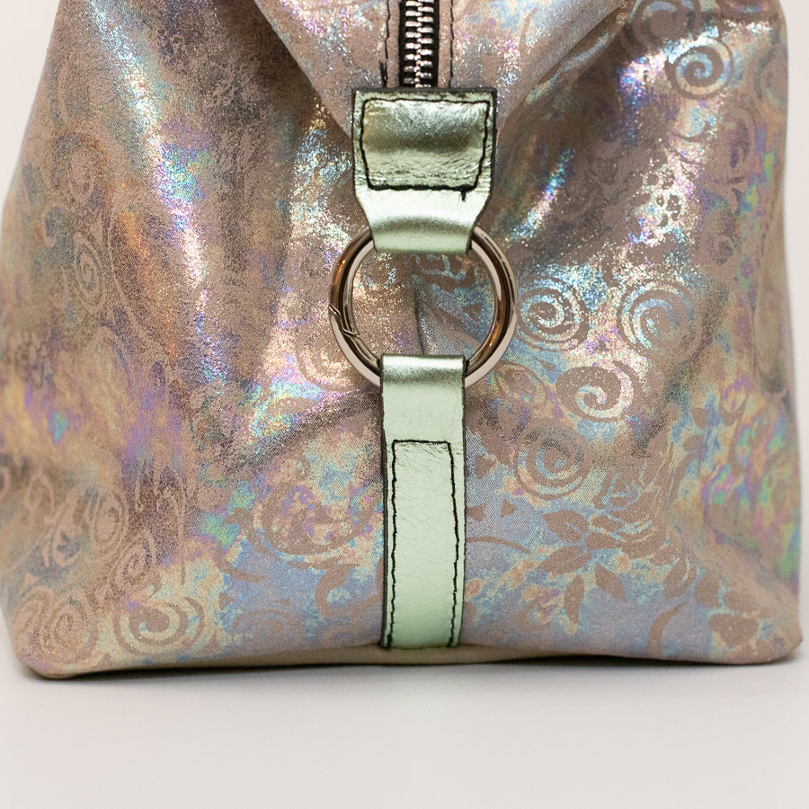 Close-up image of Vera handbag in Opaline Garden featuring silver o-ring secured iridescent Italian leather side straps 