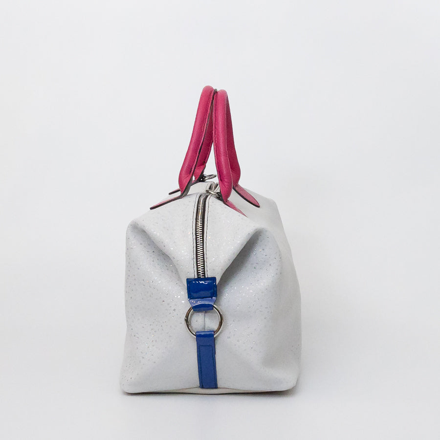 Side image of Vera handbag in Winter Orchid featuring blue leather straps with attached o-ring clasp and structured top handles